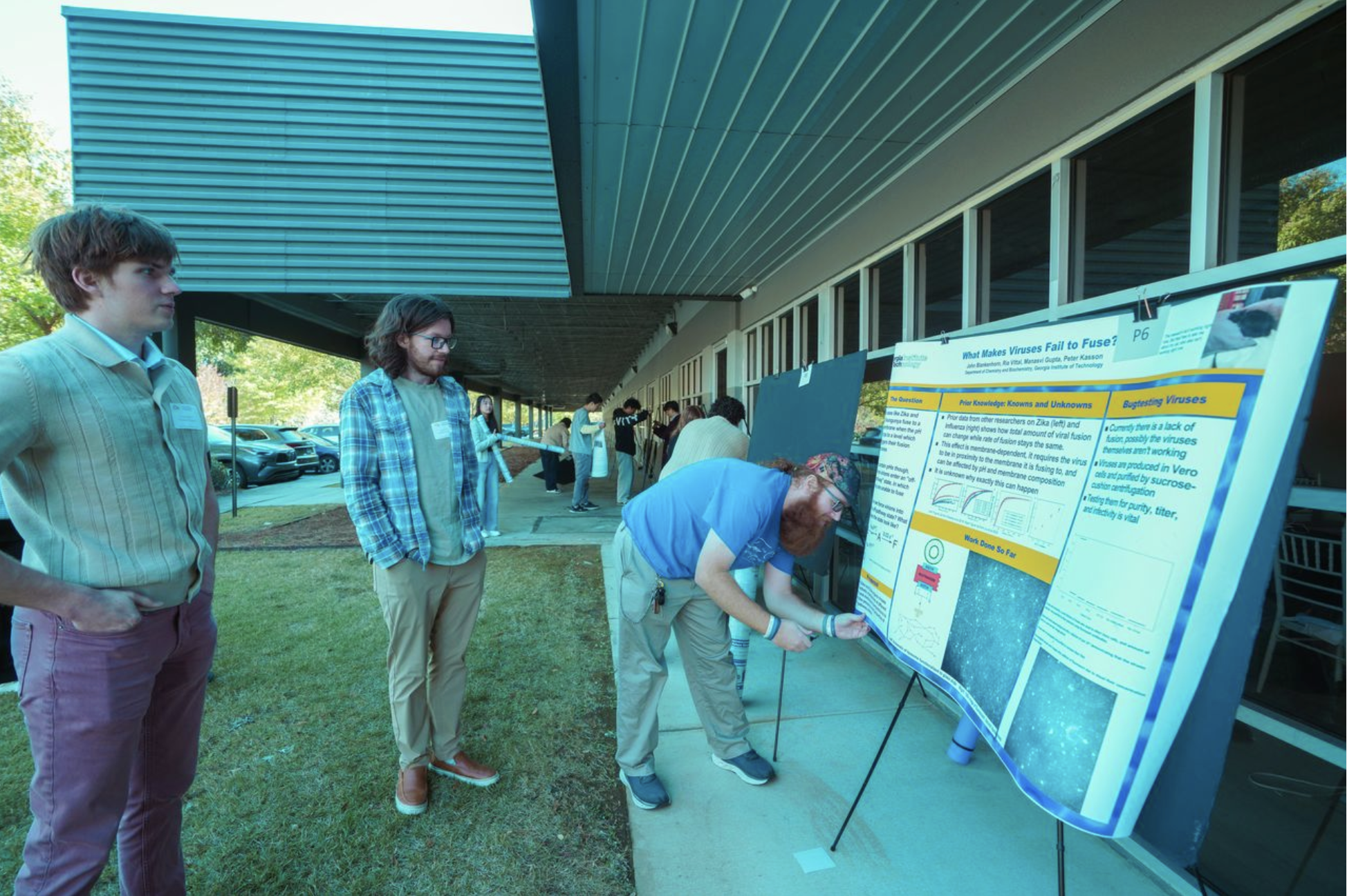 Students looking on as a poster presenter sets up